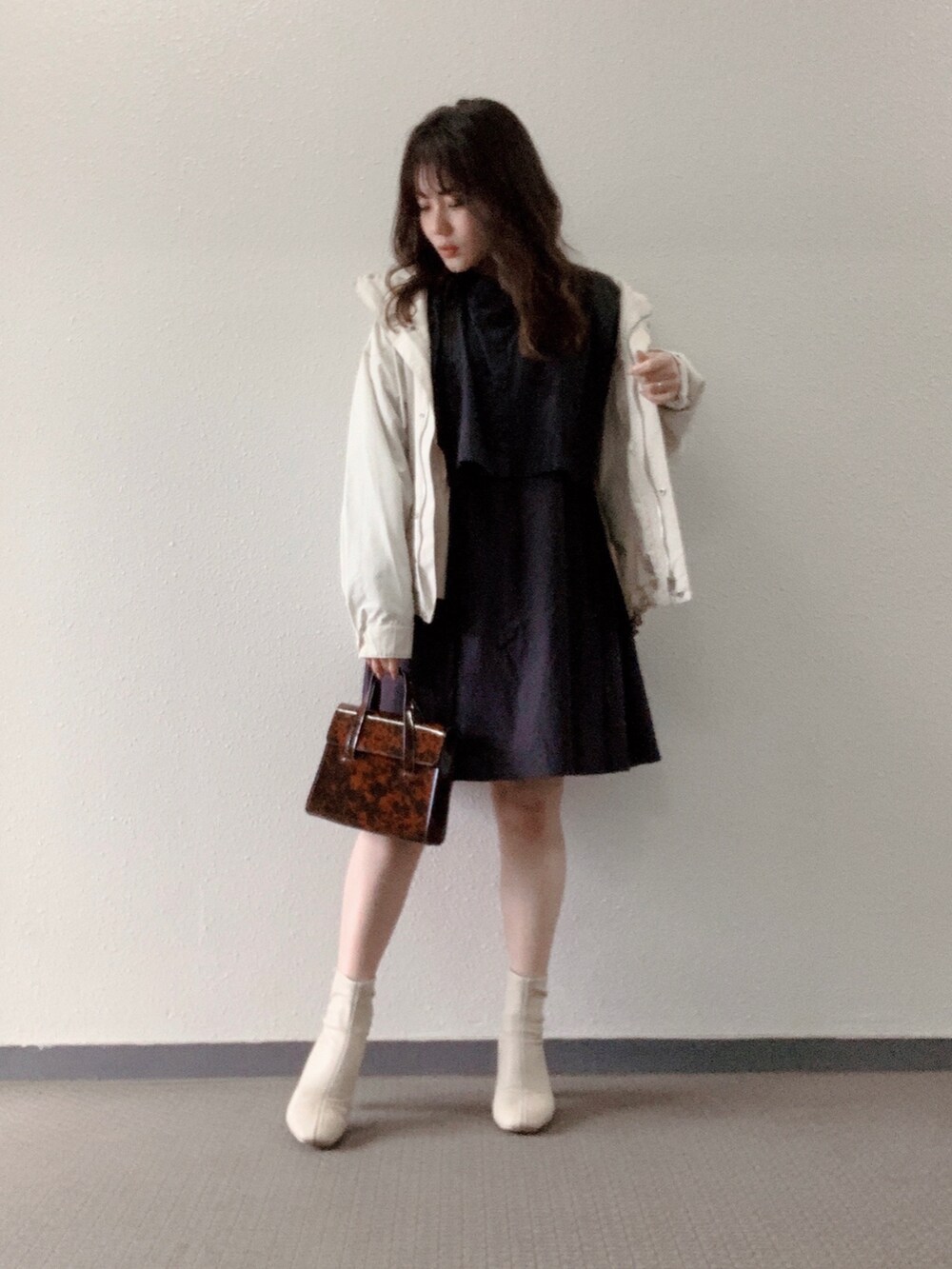 ブラウン系のハンドバッグ、ホワイト系のブーツ、ブラック系のシャツ/ブラウスを着用したレディースの春コーディネートの3枚目の写真