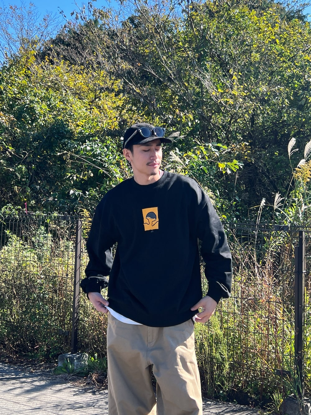 ブラック系のスウェット、ベージュ系のチノパンツを着用したメンズの冬コーディネートの2枚目の写真