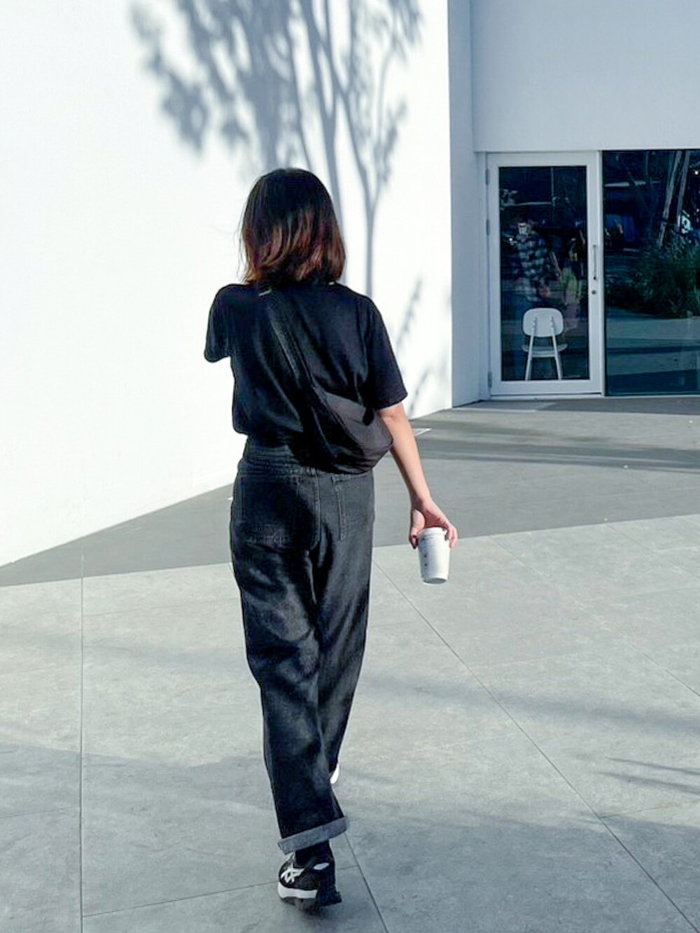 ブラック系のパンツ、ブラック系のTシャツ/カットソー、ブラック系のスニーカーを着用したレディースの春コーディネートの3枚目の写真