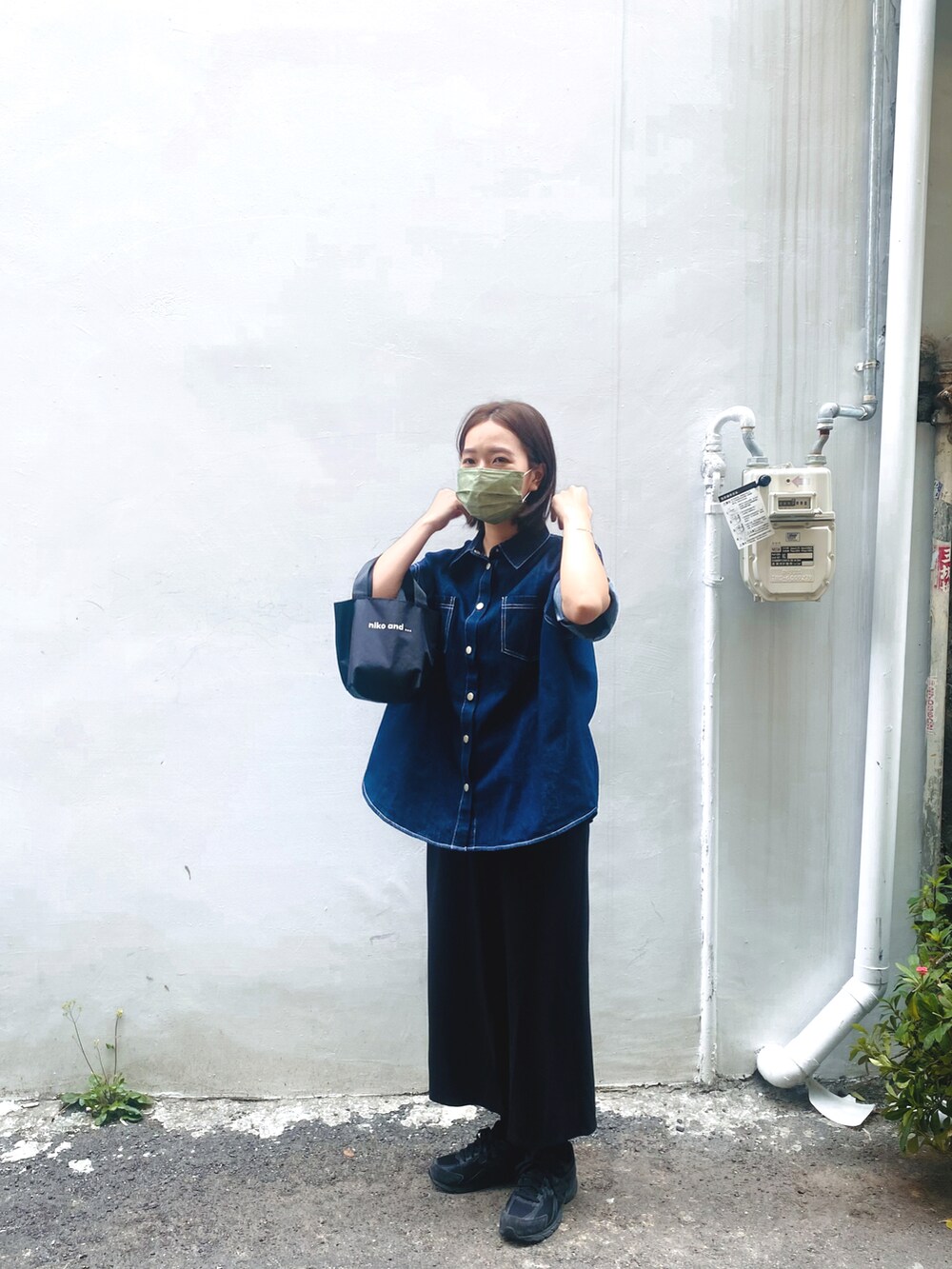 ブラック系のバッグ、ブルー系のトップス、ブラック系のスニーカーを着用したレディースの春コーディネートの2枚目の写真