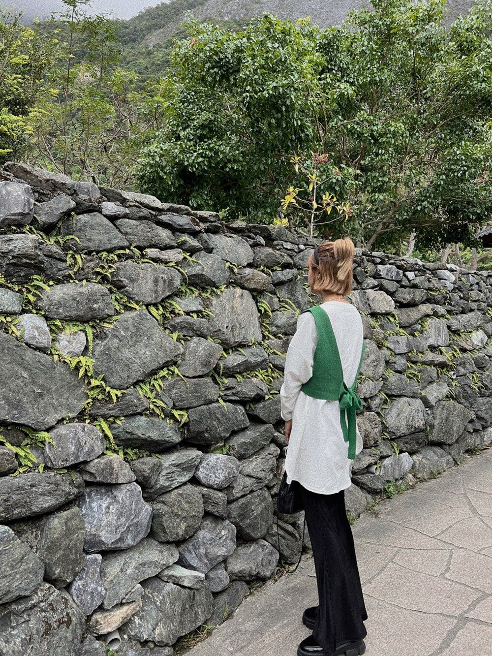 グリーン系のトップス、ブラック系のバッグを着用したレディースの秋コーディネートの4枚目の写真