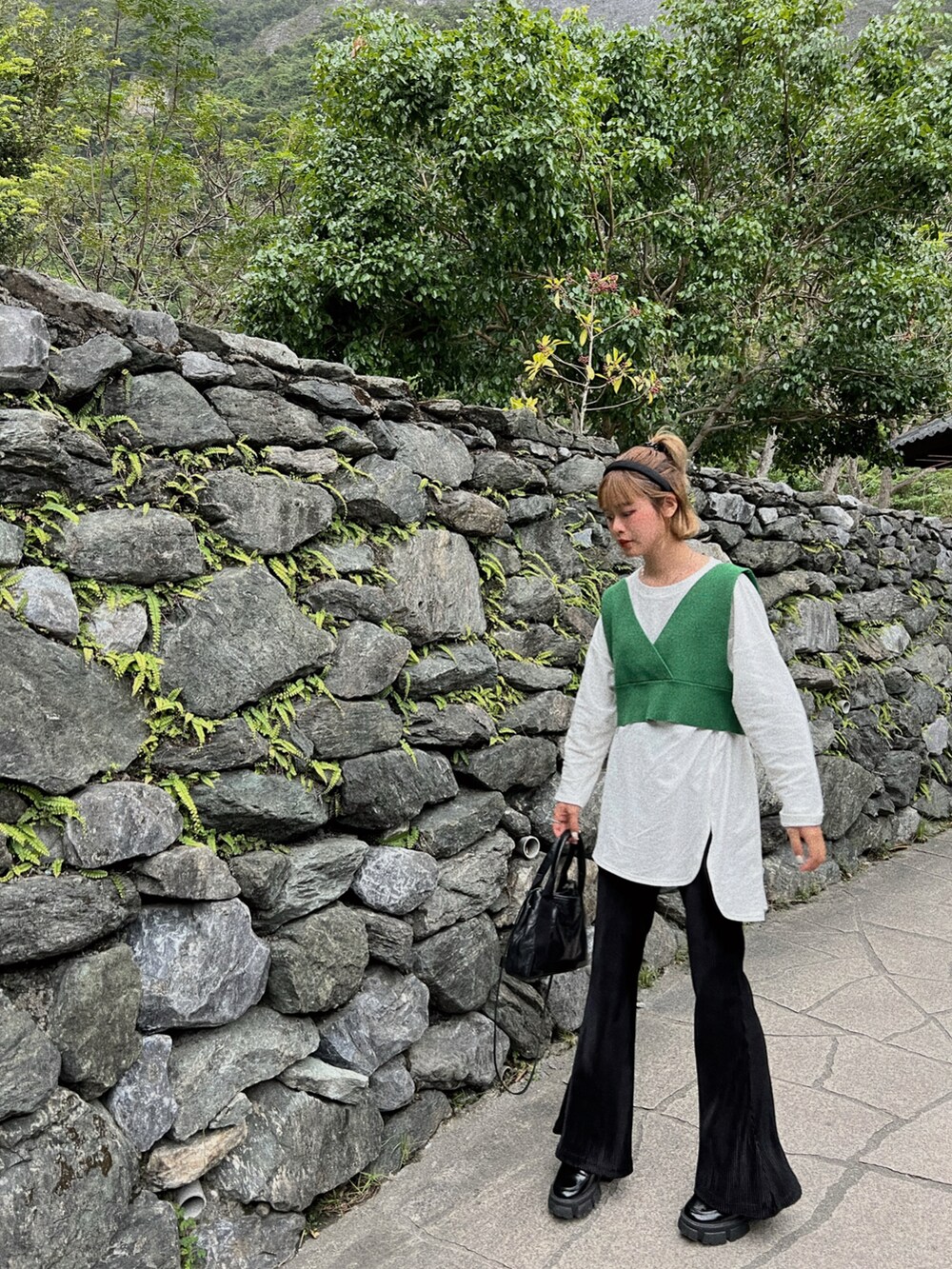 グリーン系のトップス、ブラック系のバッグを着用したレディースの秋コーディネートの2枚目の写真