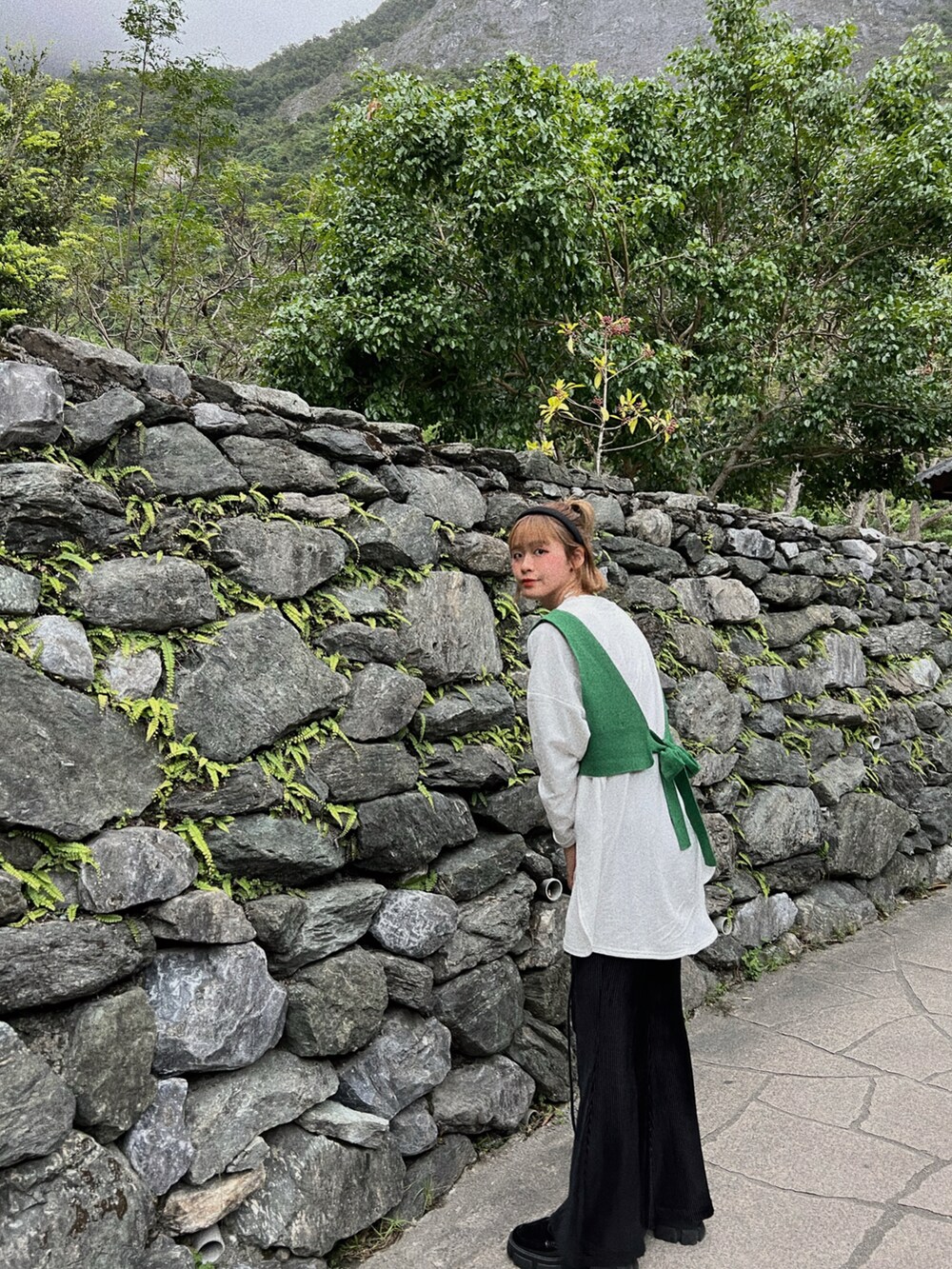 グリーン系のトップス、ブラック系のバッグを着用したレディースの秋コーディネートの3枚目の写真