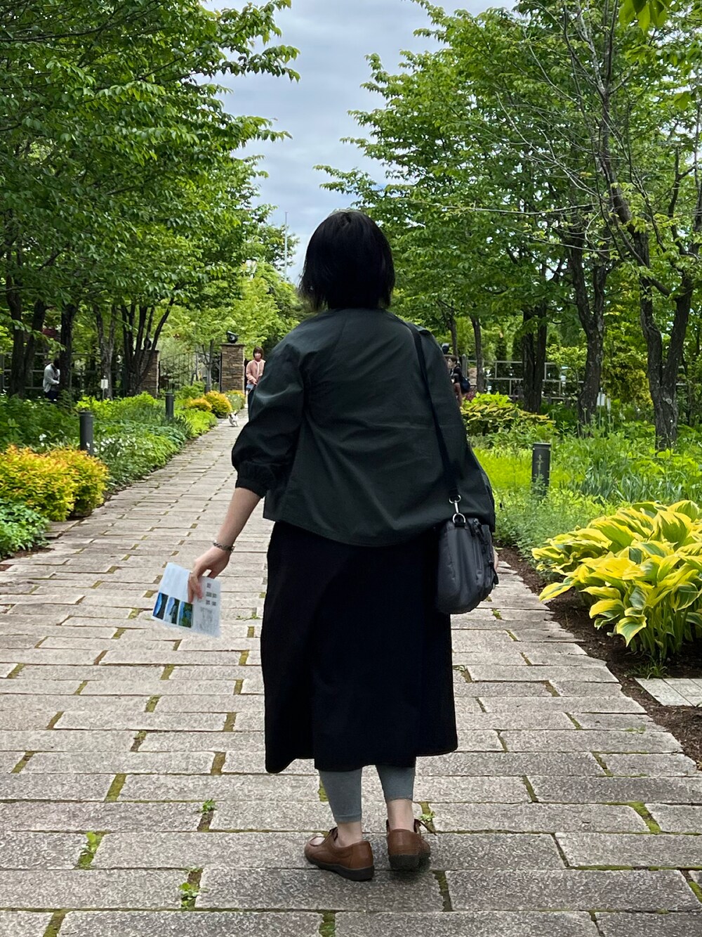 ブラック系のワンピース、グリーン系のブルゾン、グレー系のショルダーバッグを着用したレディースの夏コーディネートの2枚目の写真