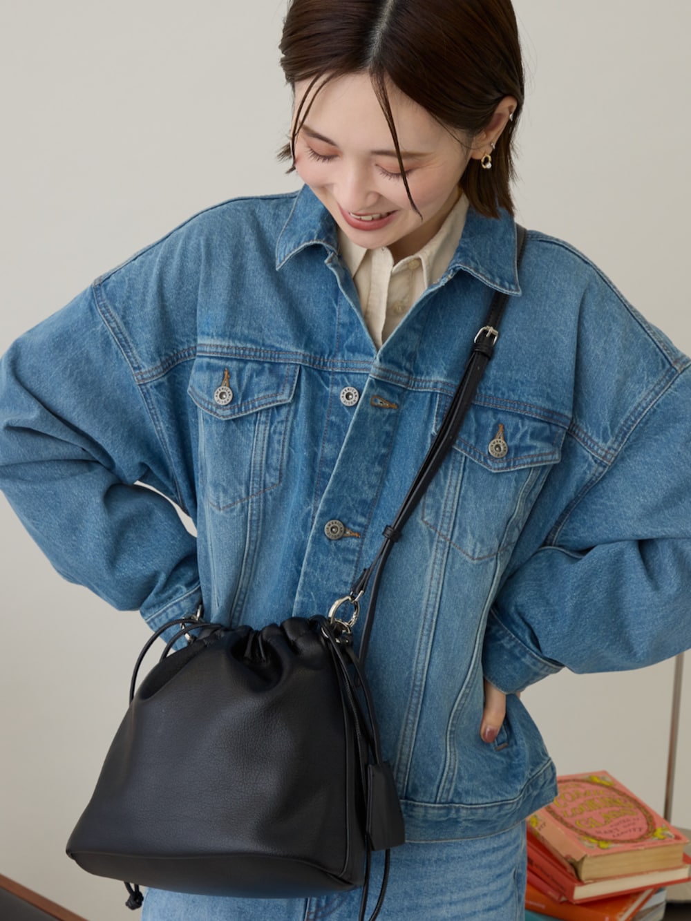ブルー系のデニムジャケット、ブルー系のスカート、ブラック系のショルダーバッグを着用したレディースの冬コーディネートの3枚目の写真