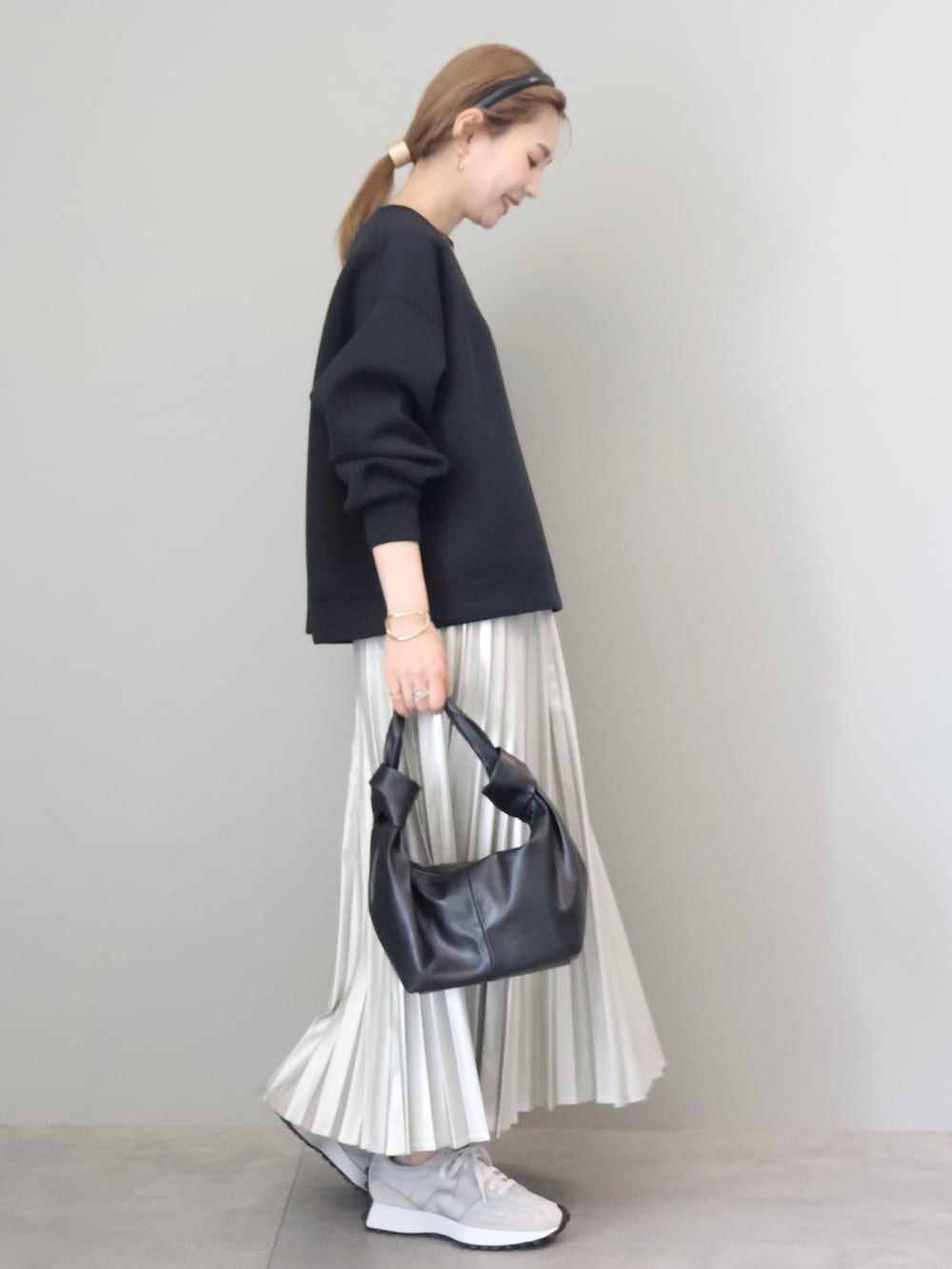 ブラック系のスウェット、シルバー系のスカート、ブラック系のハンドバッグを着用したレディースの秋コーディネートの2枚目の写真