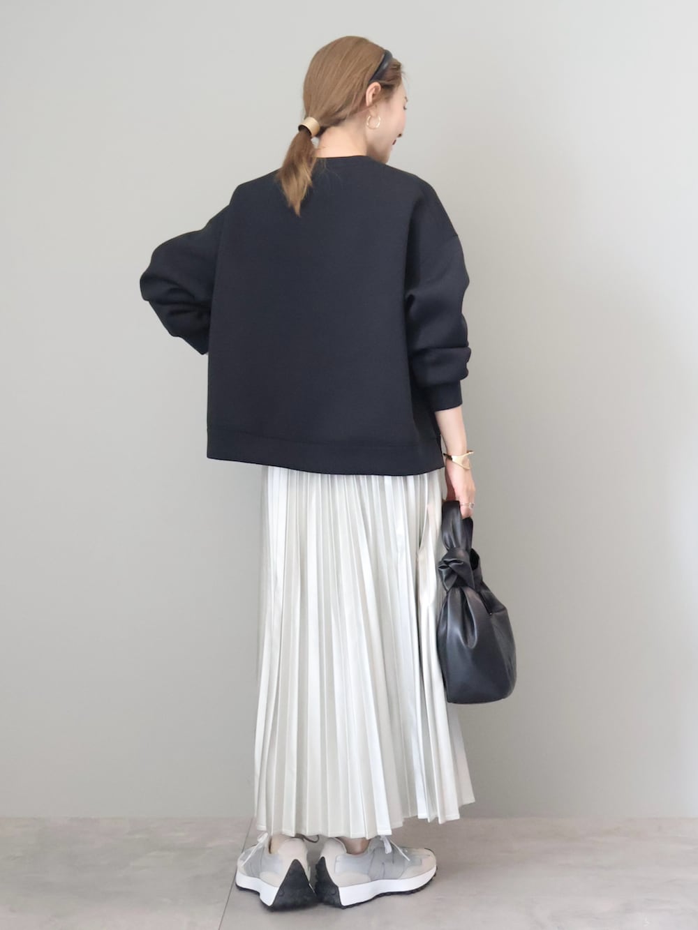 ブラック系のスウェット、シルバー系のスカート、ブラック系のハンドバッグを着用したレディースの秋コーディネートの3枚目の写真