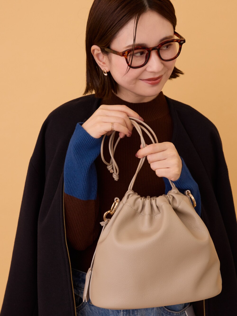 ブルー系のデニムパンツ、ブラック系のその他アウター、ブラウン系のニット/セーターを着用したレディースの冬コーディネートの6枚目の写真