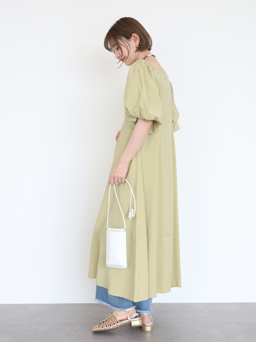 ゴールド系のサンダル、グリーン系のワンピース、ブルー系のデニムパンツを着用したレディースの春コーディネートの3枚目の写真