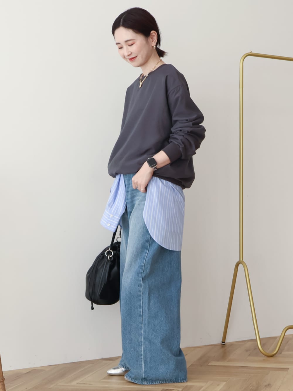 ブルー系のデニムパンツ、ブラック系のショルダーバッグ、グレー系のスウェットを着用したレディースの冬コーディネートの2枚目の写真