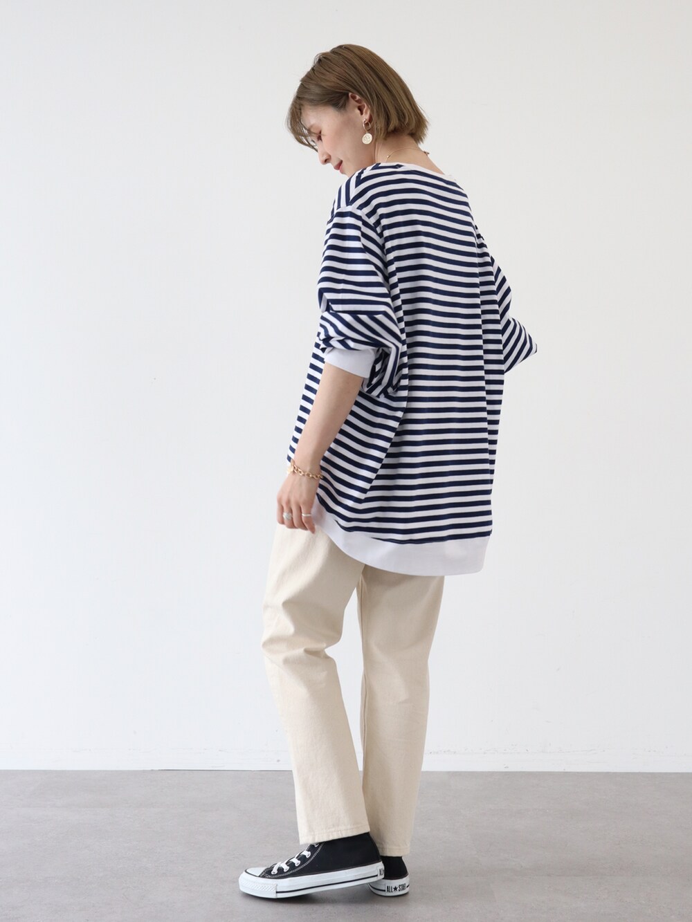 ベージュ系のデニムパンツ、ブルー系のTシャツ/カットソー、ゴールド系のピアス（両耳用）を着用したレディースの春コーディネートの2枚目の写真