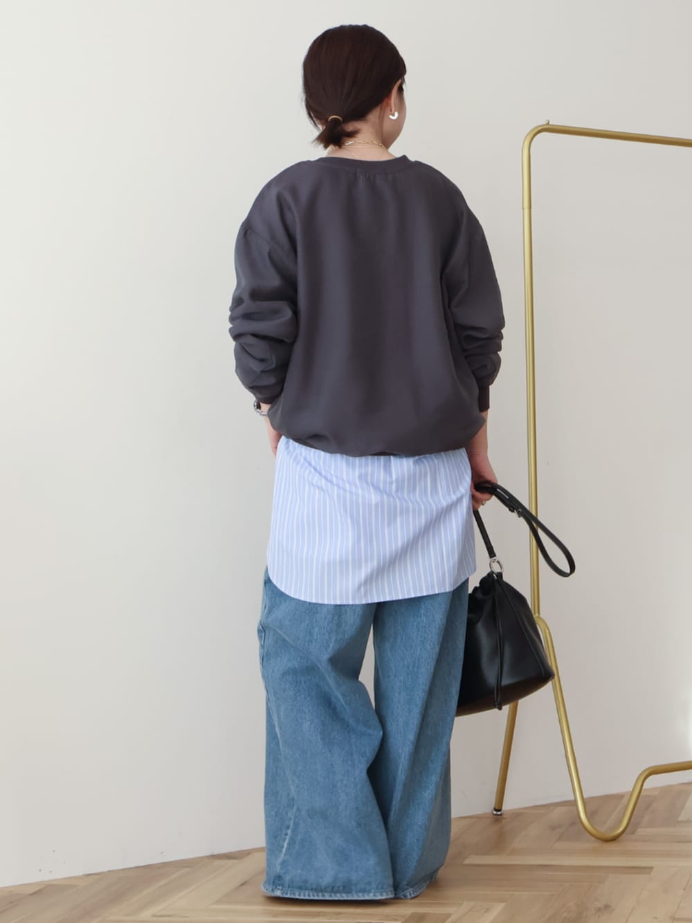 ブルー系のデニムパンツ、ブラック系のショルダーバッグ、グレー系のスウェットを着用したレディースの冬コーディネートの3枚目の写真