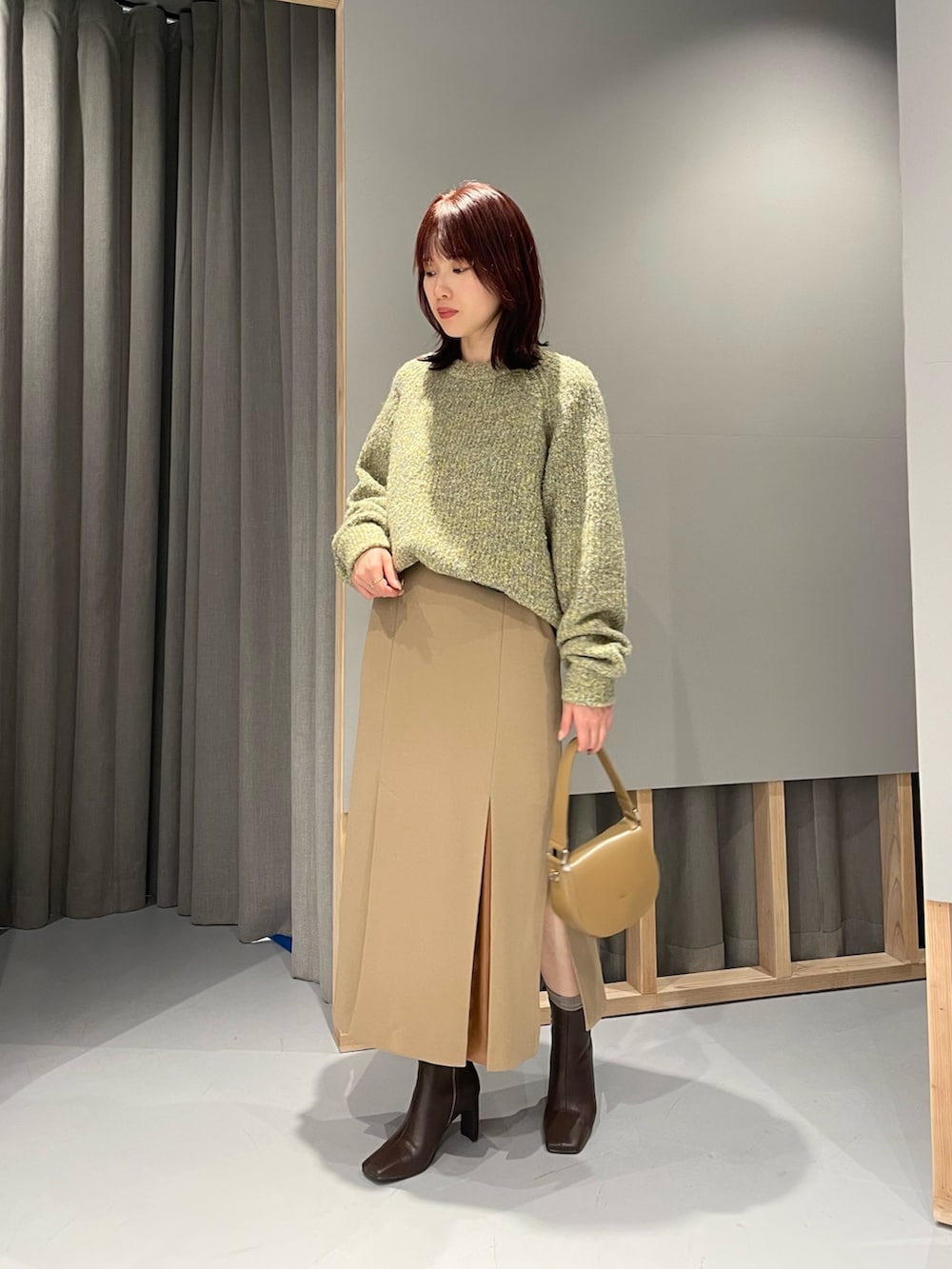 イエロー系のニット/セーター、ベージュ系のスカート、ブラウン系のブーツを着用したレディースの冬コーディネートの4枚目の写真