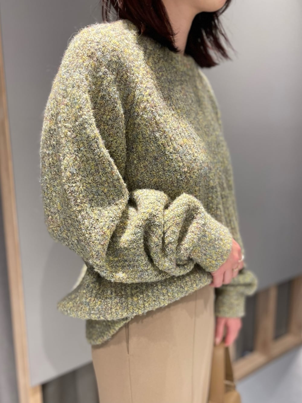 イエロー系のニット/セーター、ベージュ系のスカート、ブラウン系のブーツを着用したレディースの冬コーディネートの2枚目の写真