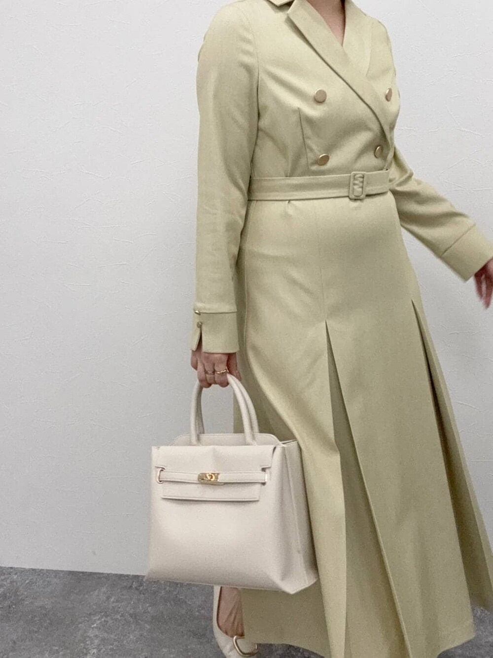 ホワイト系のトートバッグ、グリーン系のワンピースを着用したレディースの冬コーディネートの2枚目の写真