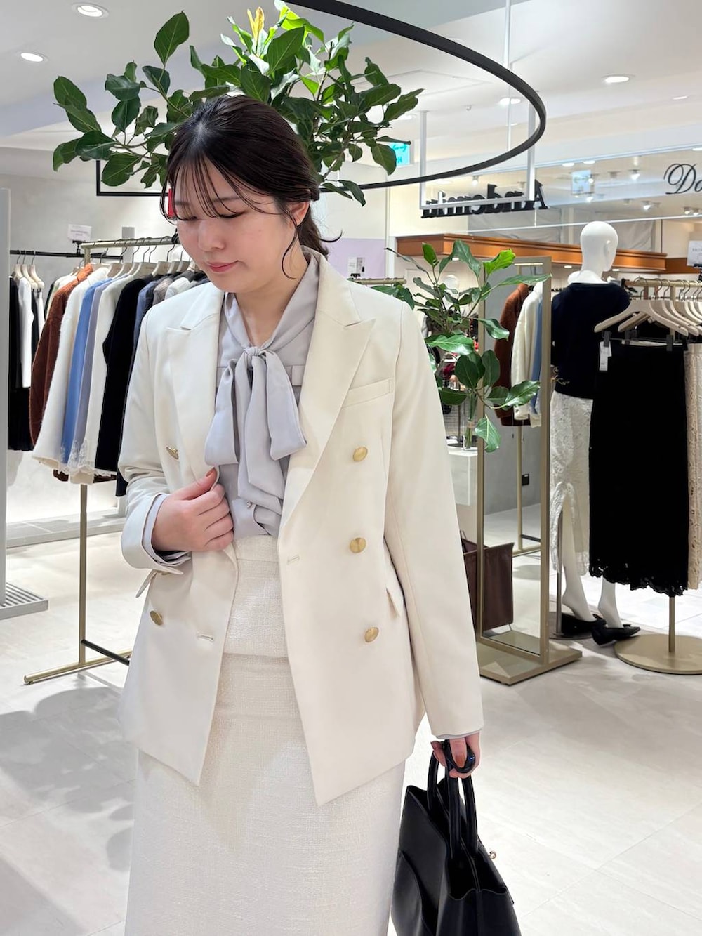 ブラック系のパンプス、ブラック系のトートバッグ、ホワイト系のテーラードジャケットを着用したレディースの春コーディネートの3枚目の写真