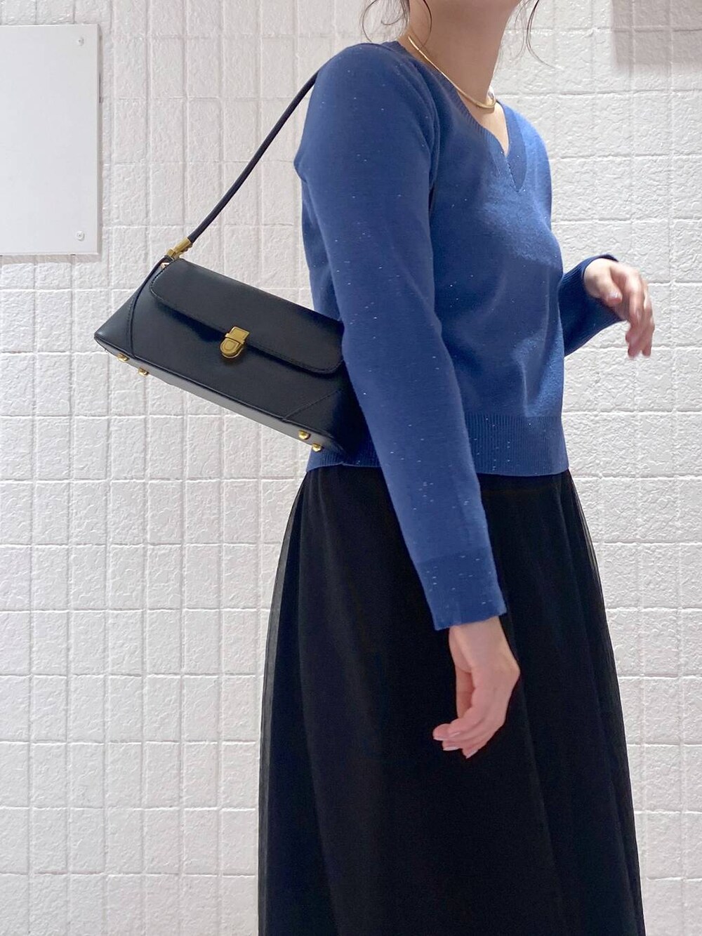 ブラック系のショルダーバッグ、ブラック系のスカート、ブラック系のブーツを着用したレディースの秋コーディネートの4枚目の写真