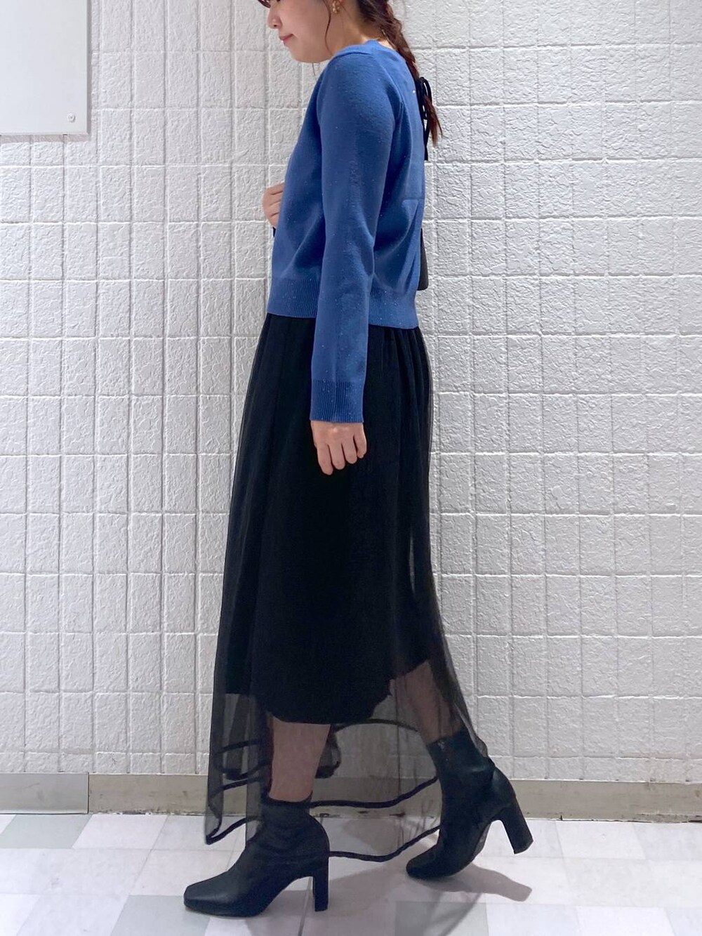 ブラック系のショルダーバッグ、ブラック系のスカート、ブラック系のブーツを着用したレディースの秋コーディネートの2枚目の写真