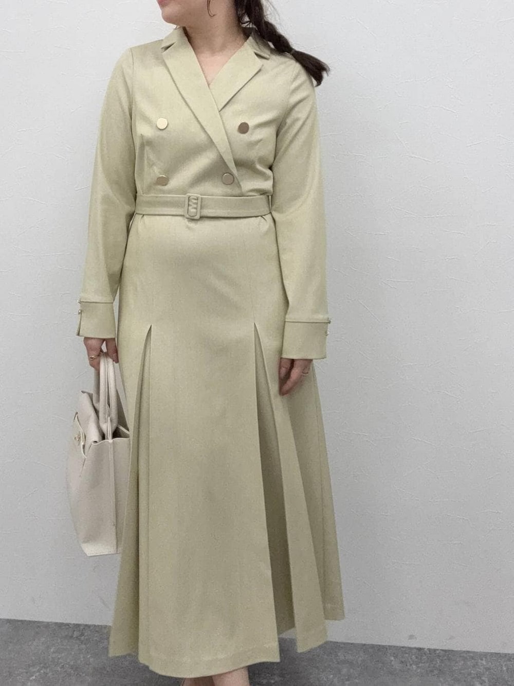 ホワイト系のトートバッグ、グリーン系のワンピースを着用したレディースの冬コーディネートの4枚目の写真