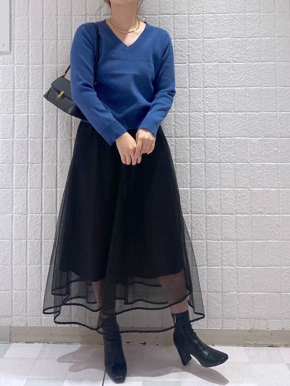 ブラック系のショルダーバッグ、ブラック系のスカート、ブラック系のブーツを着用したレディースの秋コーディネートの3枚目の写真