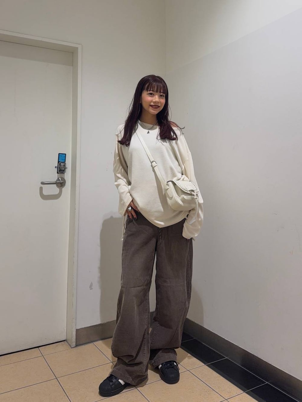 ホワイト系のショルダーバッグ、ブラウン系のその他パンツ、ホワイト系のTシャツ/カットソーを着用したレディースの秋コーディネートの3枚目の写真