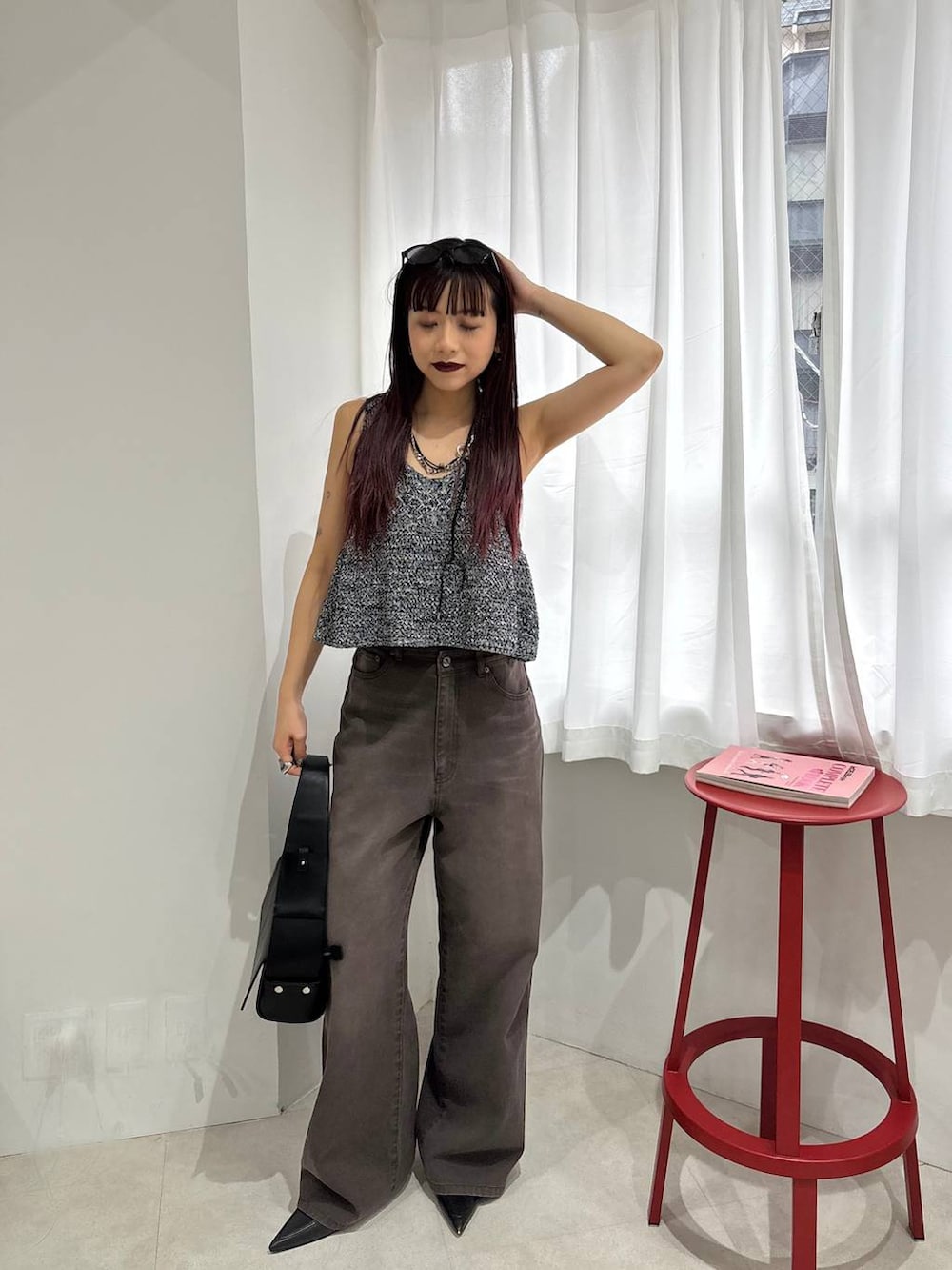 ブラック系のショルダーバッグ、ブラウン系のデニムパンツ、ブラック系のベストを着用したレディースの春コーディネートの5枚目の写真