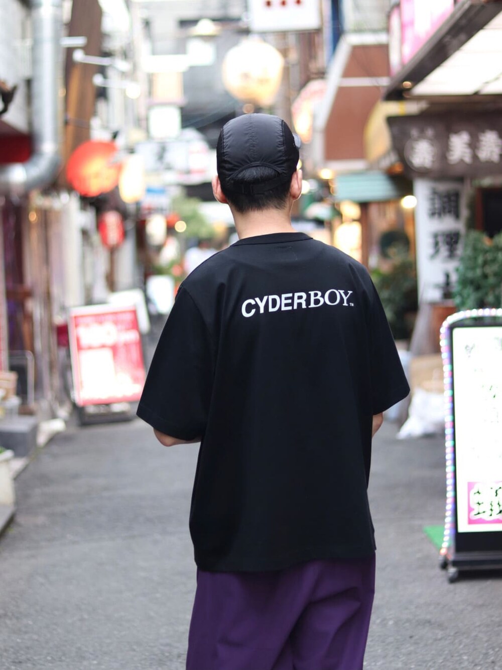 ブラック系のTシャツ/カットソー、パープル系のスラックス、ベージュ系のショルダーバッグを着用したメンズの夏コーディネートの3枚目の写真