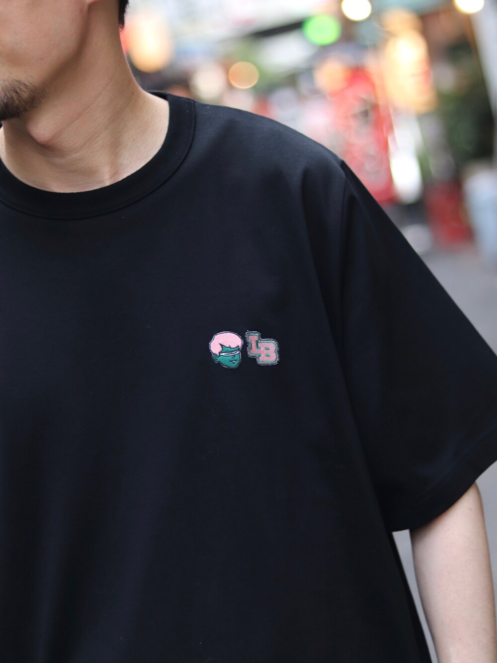 ブラック系のTシャツ/カットソー、パープル系のスラックス、ベージュ系のショルダーバッグを着用したメンズの夏コーディネートの5枚目の写真