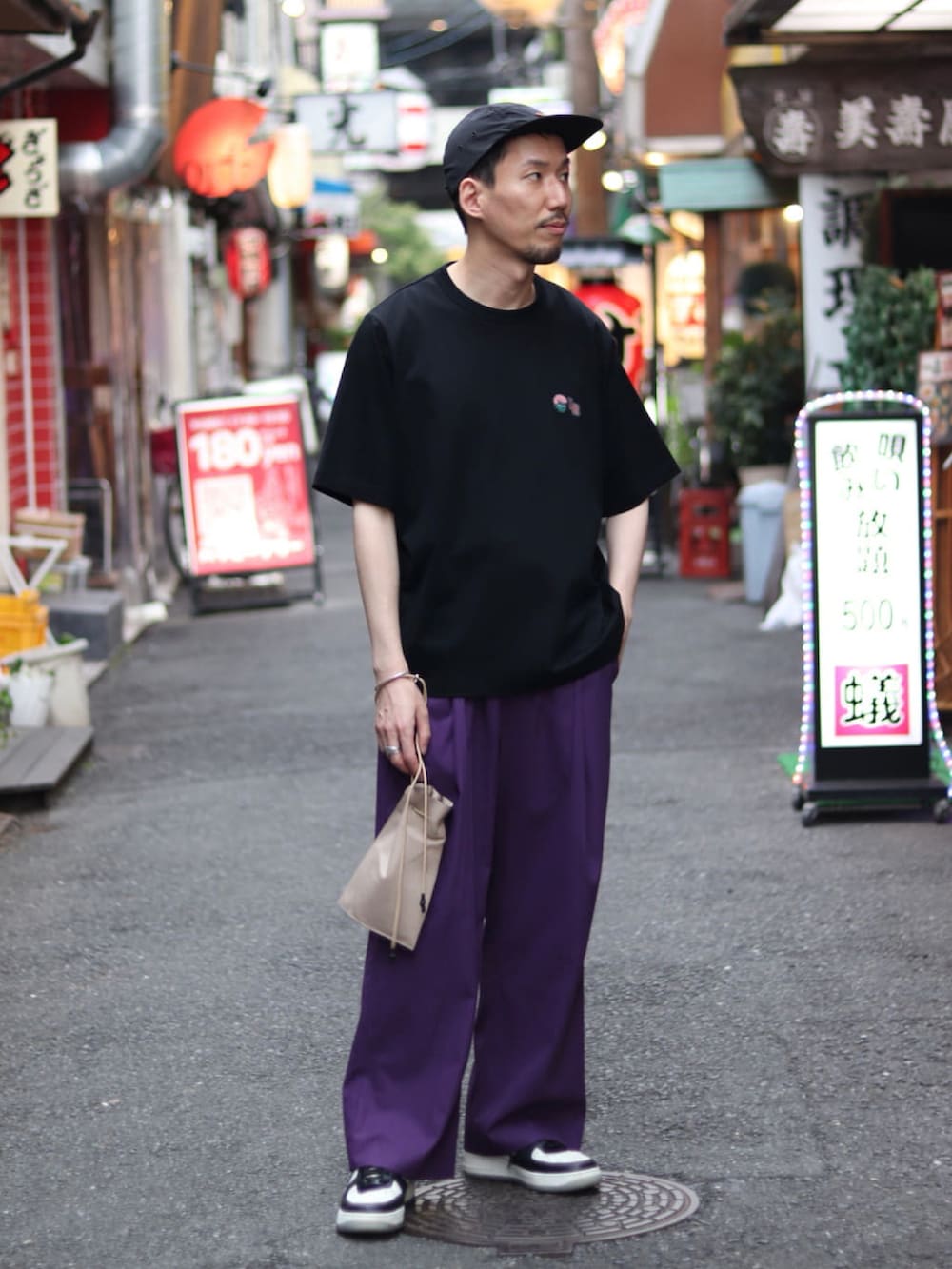 ブラック系のTシャツ/カットソー、パープル系のスラックス、ベージュ系のショルダーバッグを着用したメンズの夏コーディネートの2枚目の写真