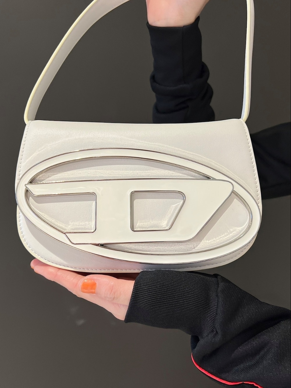 ブラック系のスウェット、ブラック系のワンピース、ホワイト系のショルダーバッグを着用したレディースの春コーディネートの3枚目の写真