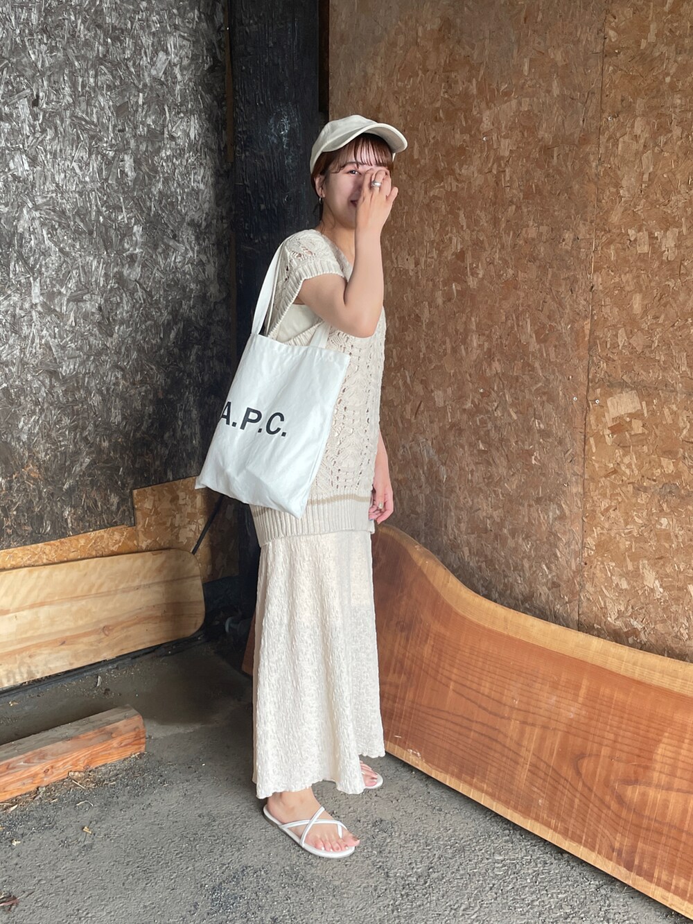 ベージュ系のベスト、ホワイト系のトートバッグ、ホワイト系のスカートを着用したレディースの夏コーディネートの3枚目の写真