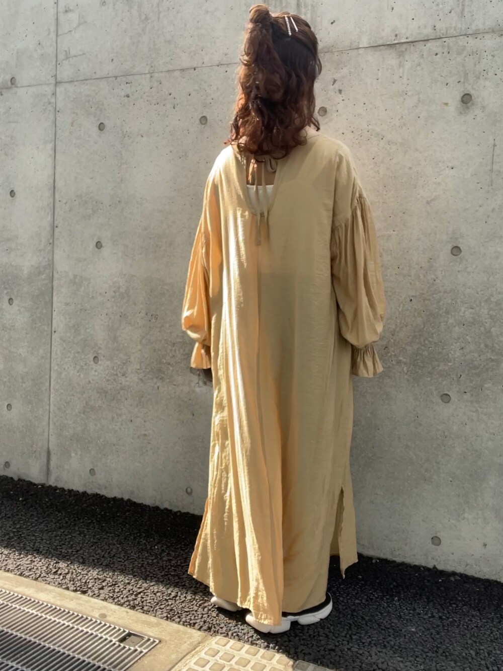 イエロー系のワンピース、ブラック系のスニーカー、ブルー系のデニムパンツを着用したレディースの夏コーディネートの2枚目の写真