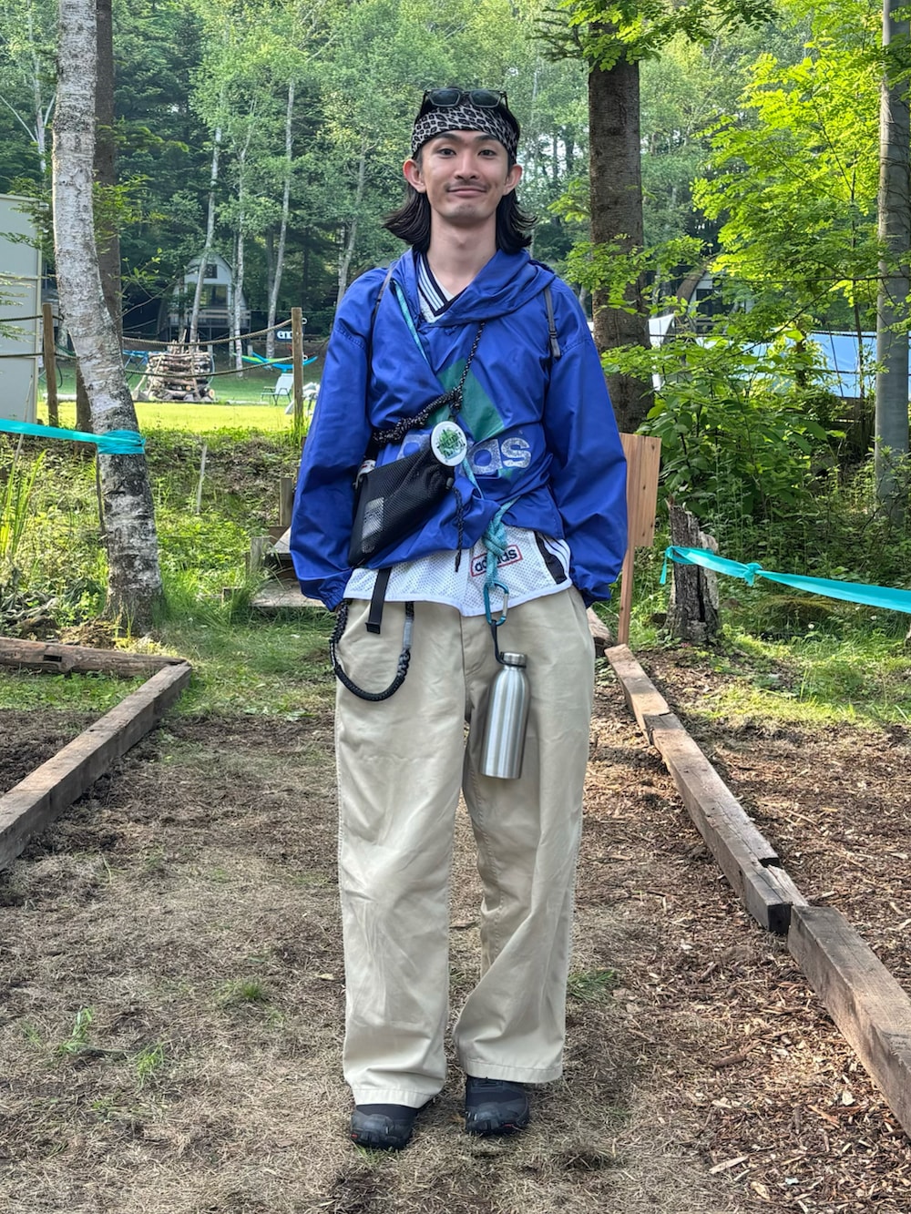 ブルー系のマウンテンパーカー、ベージュ系のチノパンツ、ブラック系のシューズを着用したメンズの夏コーディネートの2枚目の写真