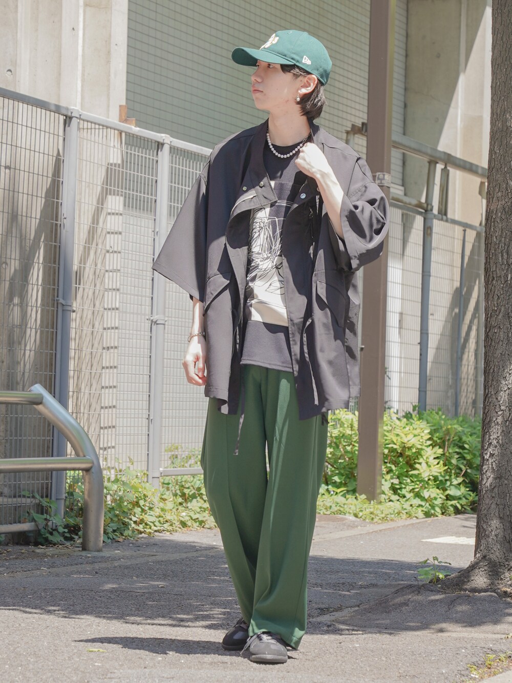 ブラック系のTシャツ/カットソー、グリーン系のスラックス、ブラック系のスニーカーを着用したメンズの春コーディネートの2枚目の写真