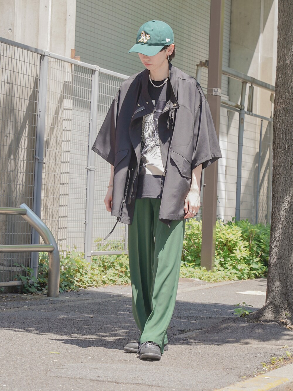 ブラック系のTシャツ/カットソー、グリーン系のスラックス、ブラック系のスニーカーを着用したメンズの春コーディネートの3枚目の写真