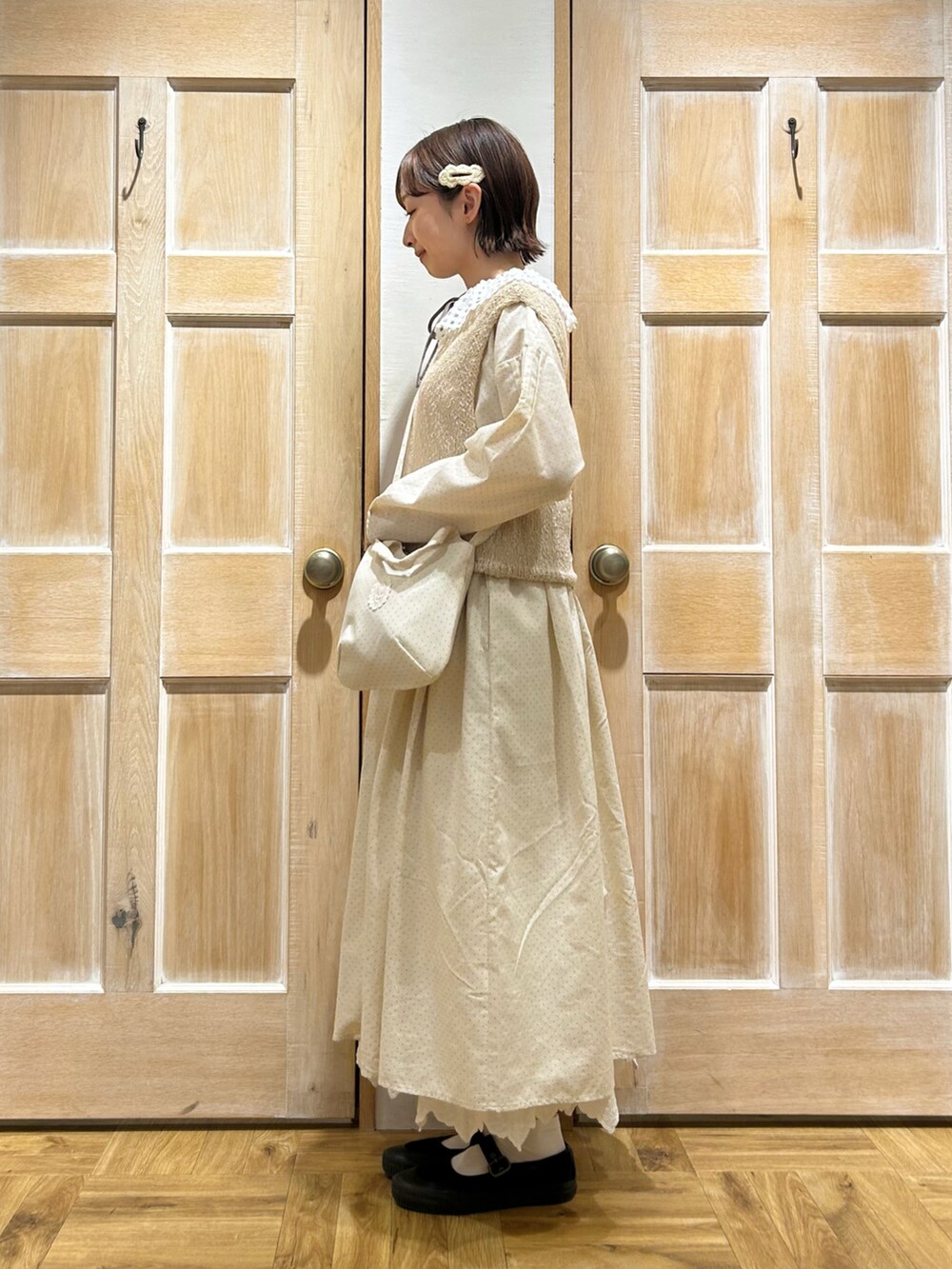 ブラウン系のシャツ/ブラウス、ホワイト系のベスト、ホワイト系のワンピースを着用したレディースの春コーディネートの2枚目の写真