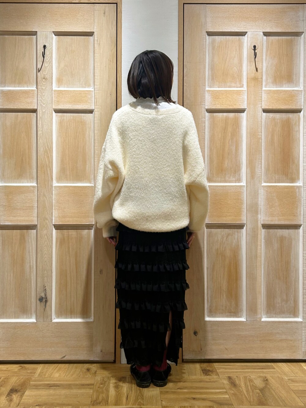 ホワイト系のニット/セーター、ホワイト系のTシャツ/カットソー、ブラック系のスカートを着用したレディースの冬コーディネートの3枚目の写真