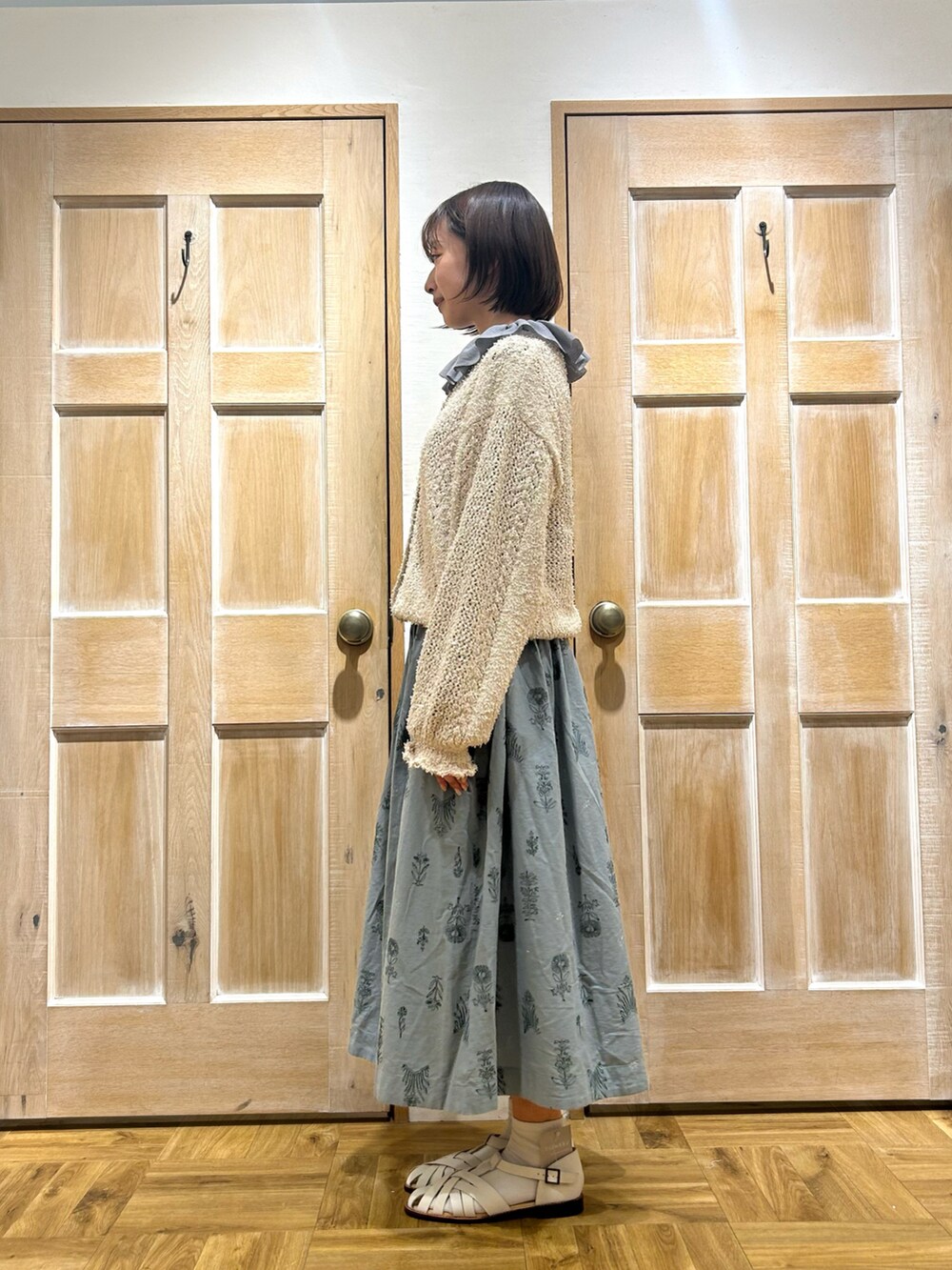 ホワイト系のカーディガン/ボレロ、ブルー系のスカート、ホワイト系のサンダルを着用したレディースの春コーディネートの2枚目の写真