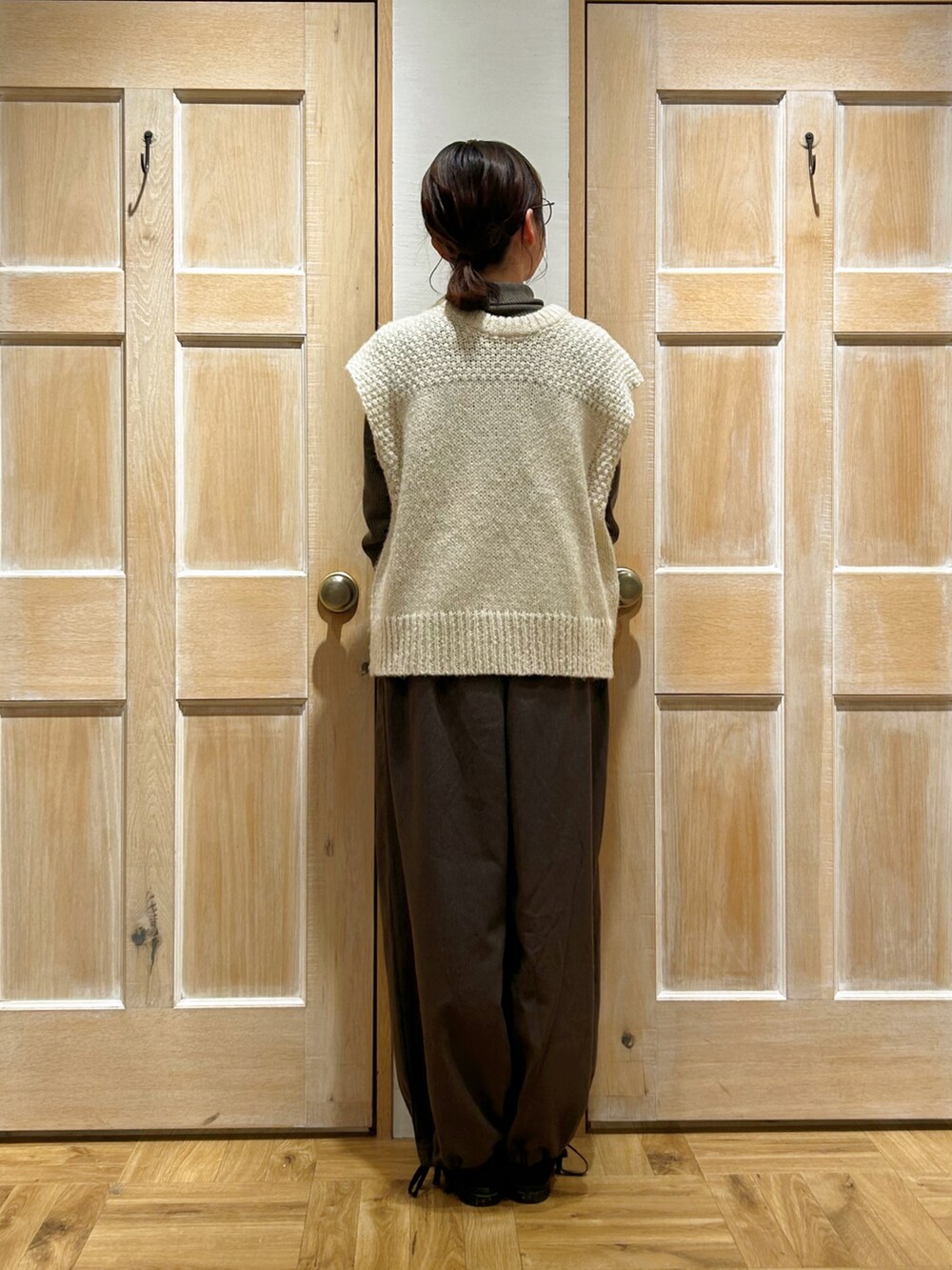 ホワイト系のベスト、ブラウン系のニット/セーター、ブラック系のハンドバッグを着用したレディースの冬コーディネートの3枚目の写真