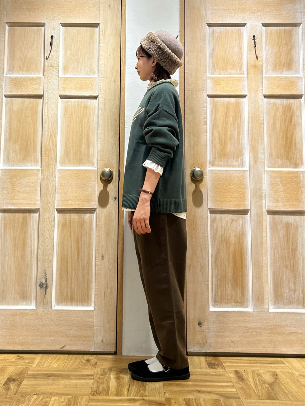 グリーン系のニット/セーター、ホワイト系のシャツ/ブラウス、ブラウン系のその他パンツを着用したレディースの秋コーディネートの2枚目の写真