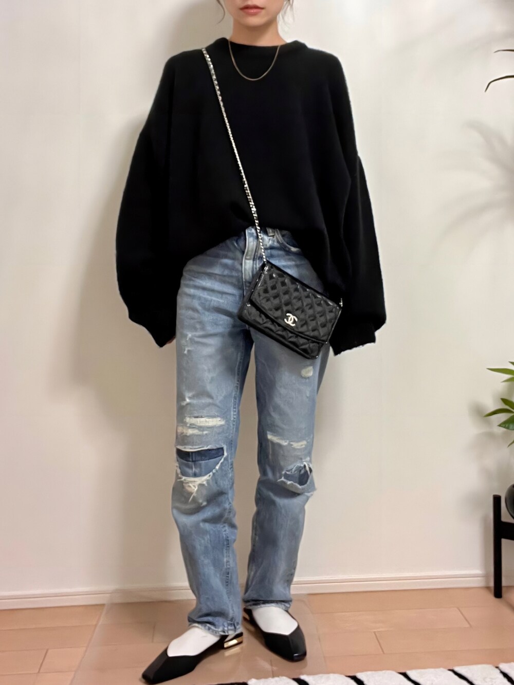 ブラック系のニット/セーター、ブルー系のデニムパンツ、ブラック系のサンダルを着用したレディースの秋コーディネートの3枚目の写真