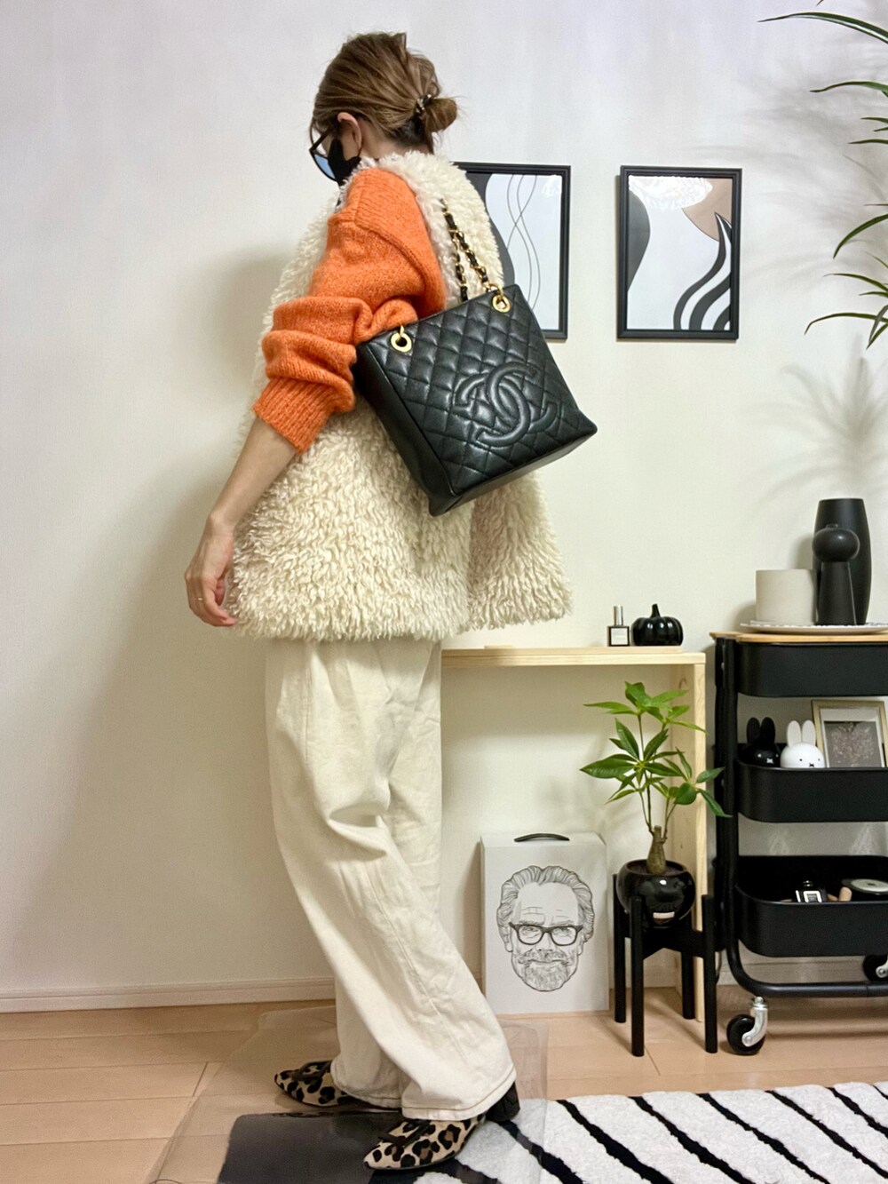 オレンジ系のニット/セーター、ホワイト系のベスト、ホワイト系のデニムパンツを着用したレディースの秋コーディネートの2枚目の写真