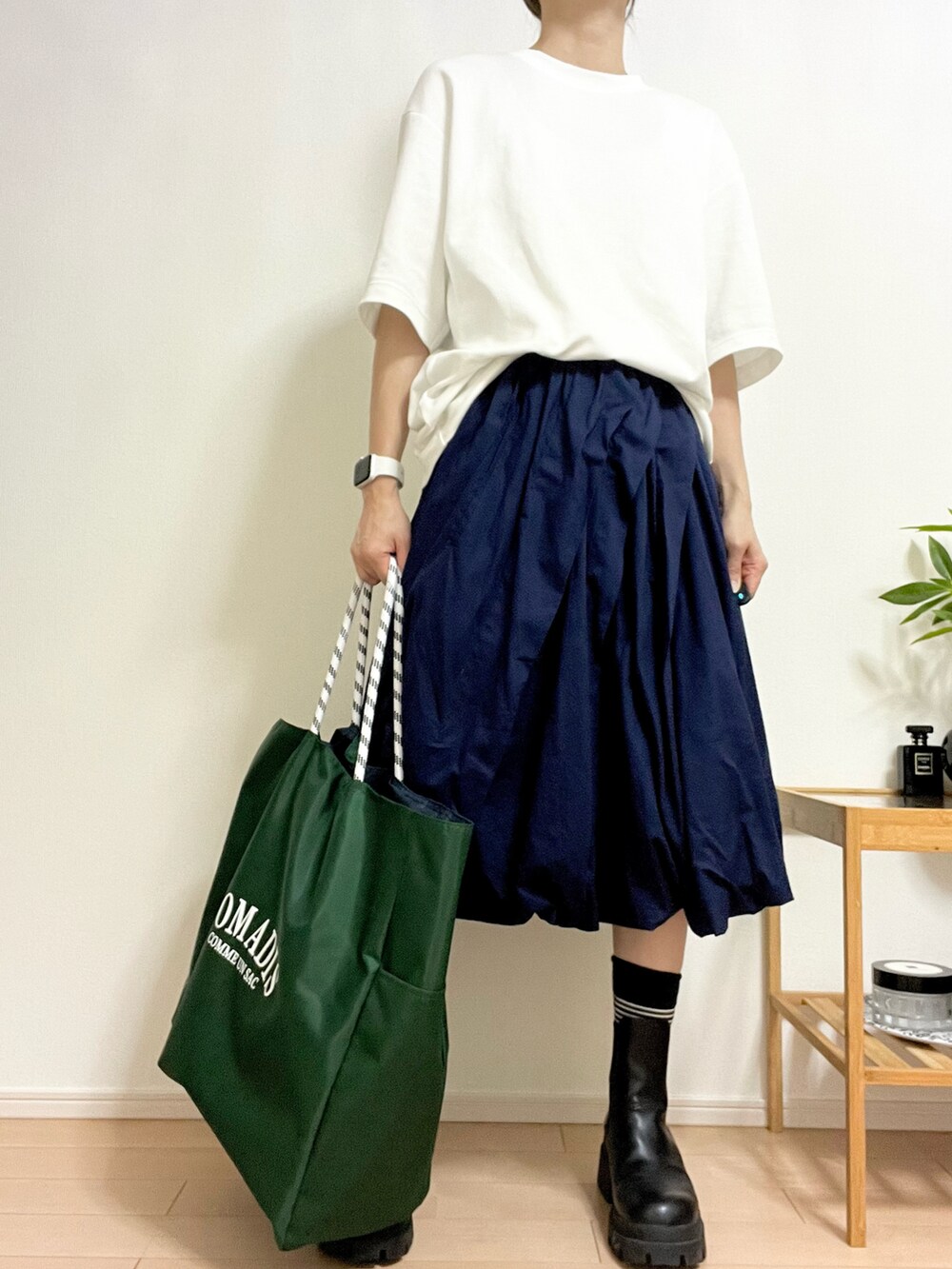 グリーン系のトートバッグ、ブルー系のスカート、ブラック系のブーツを着用したレディースの夏コーディネートの2枚目の写真