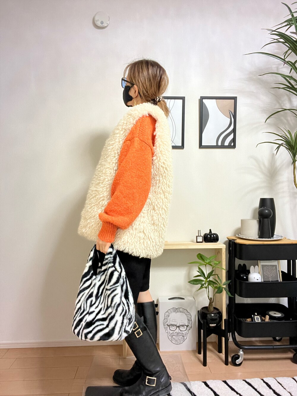 オレンジ系のニット/セーター、ホワイト系のベスト、ブラック系のその他パンツを着用したレディースの秋コーディネートの2枚目の写真