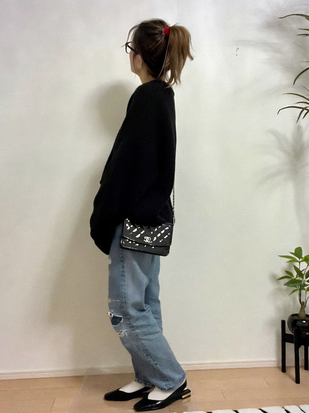 ブラック系のニット/セーター、ブルー系のデニムパンツ、ブラック系のサンダルを着用したレディースの秋コーディネートの2枚目の写真