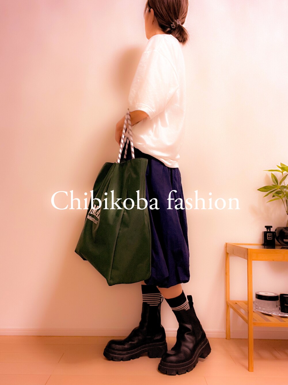 グリーン系のトートバッグ、ブルー系のスカート、ブラック系のブーツを着用したレディースの夏コーディネートの3枚目の写真