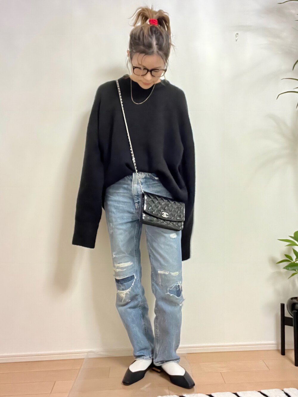 ブラック系のニット/セーター、ブルー系のデニムパンツ、ブラック系のサンダルを着用したレディースの秋コーディネートの4枚目の写真