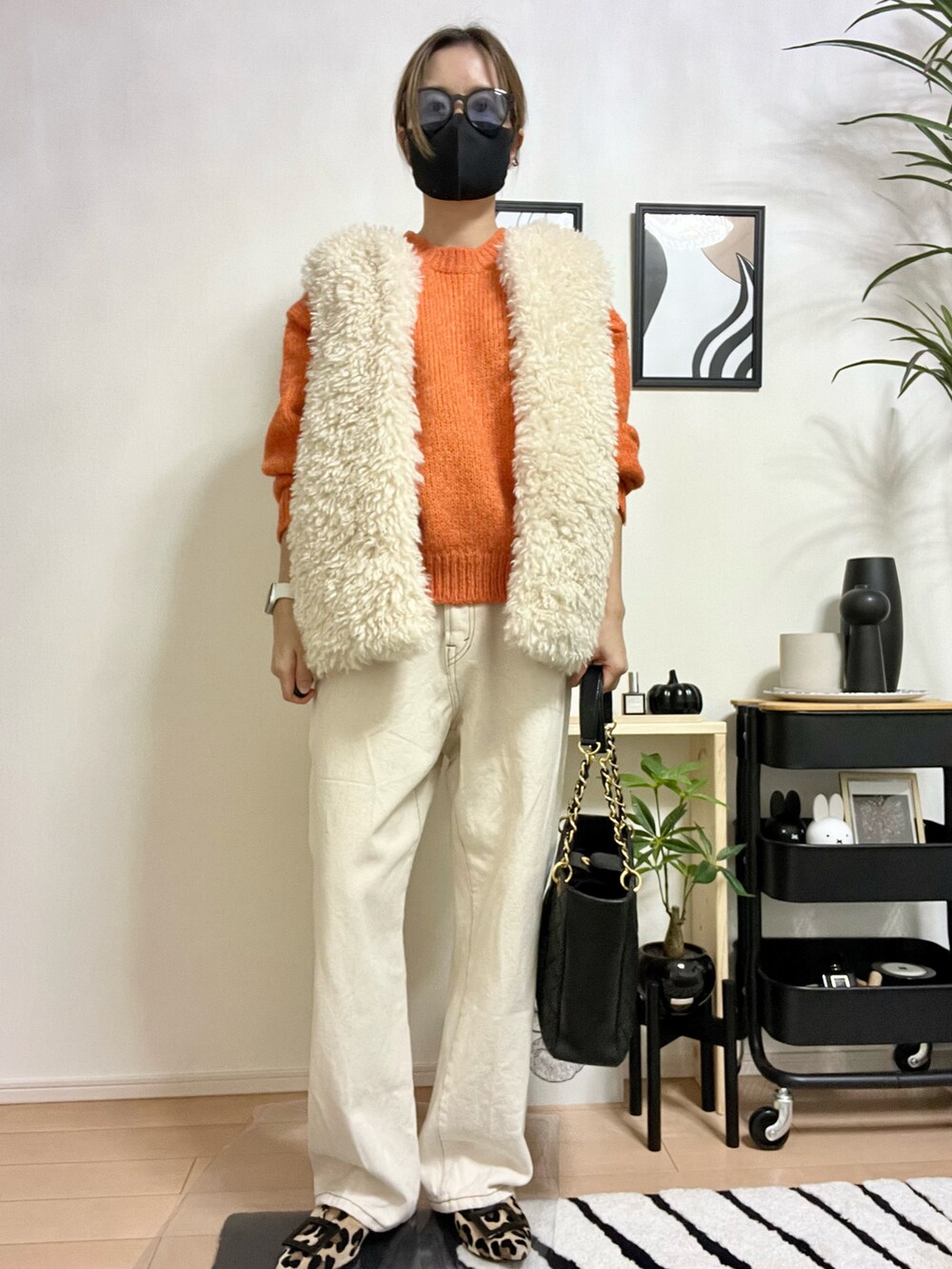 オレンジ系のニット/セーター、ホワイト系のベスト、ホワイト系のデニムパンツを着用したレディースの秋コーディネートの3枚目の写真