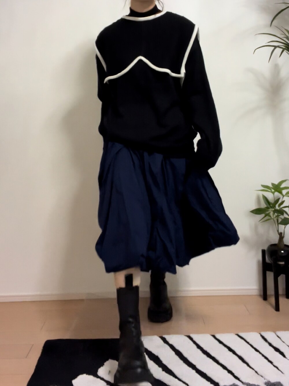 ブラック系のニット/セーター、ブルー系のスカート、ブラック系のブーツを着用したレディースの秋コーディネートの4枚目の写真