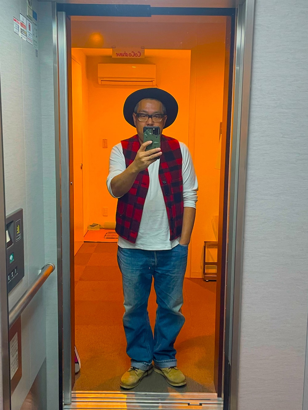 レッド系のベスト、ホワイト系のTシャツ/カットソー、ブルー系のデニムパンツを着用したメンズの冬コーディネートの2枚目の写真